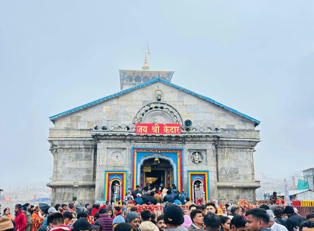 A large crowd gathers at the historic Kedarnath Temple in India amidst misty weather.